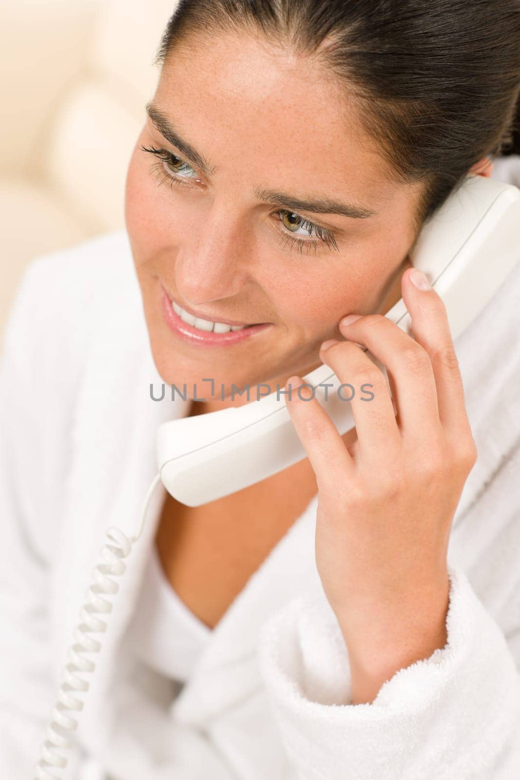 Portrait of attractive mid-aged woman speaking on phone wearing bathrobe
