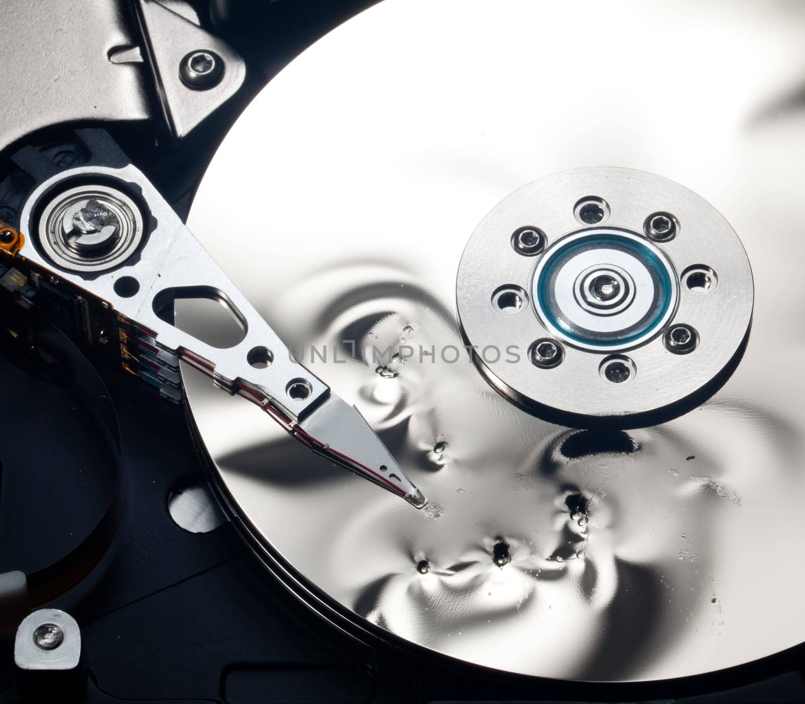 Magnetic disc inside a damaged computer hd unit showing mirror surface of the magnetic discs and read write head
