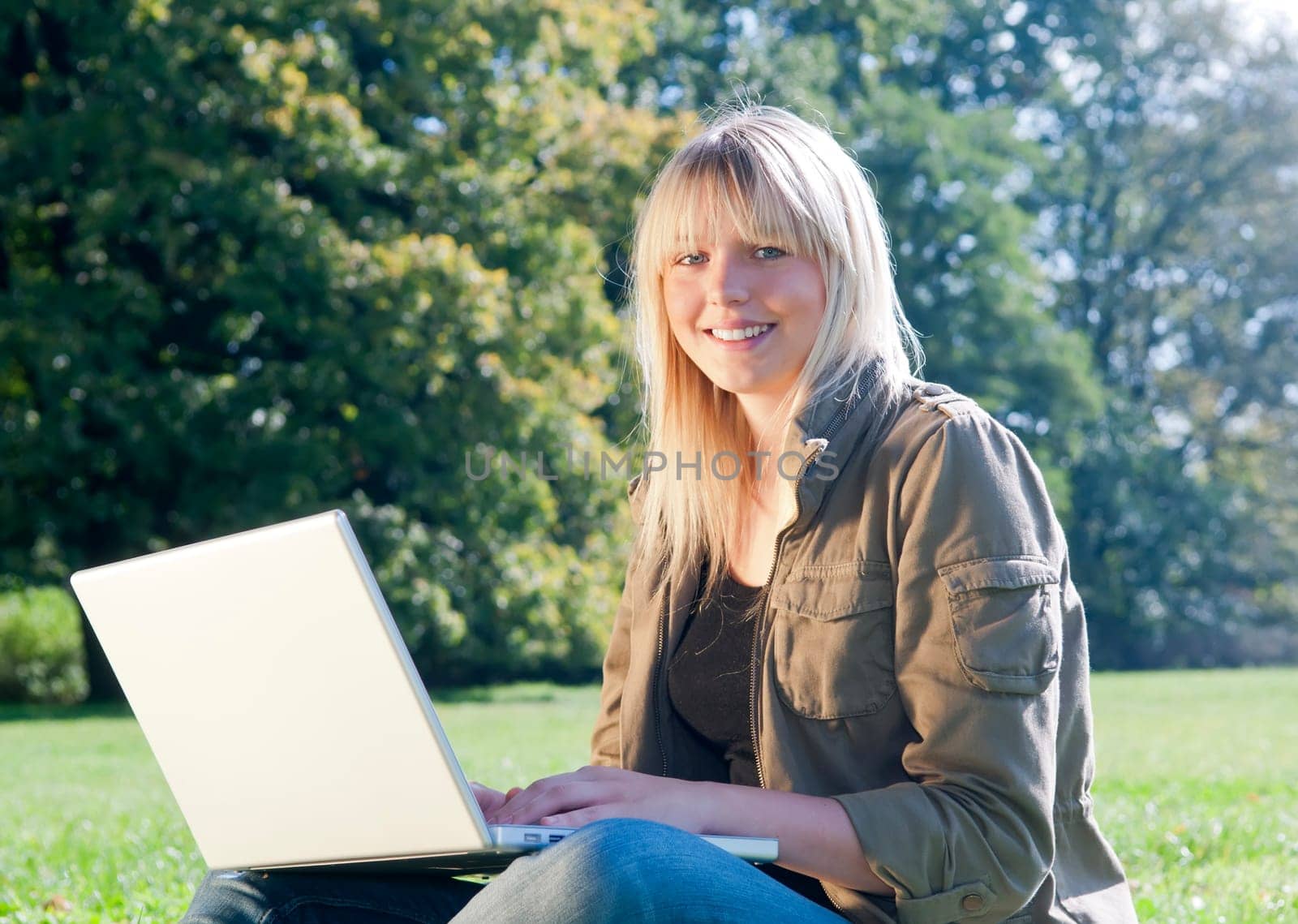 Young woman with laptop in a meadow