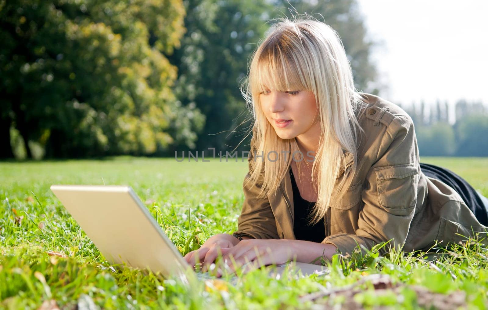 Young woman with laptop in a meadow