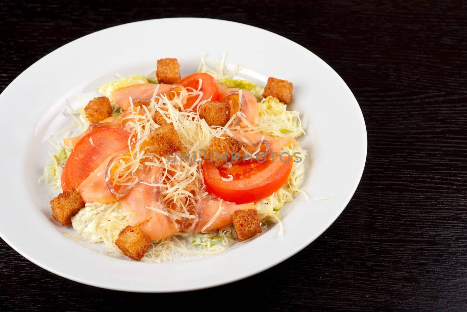 Salad of lettuce, chinese cabbage, tomato, garlic rusk, parmesan cheese, sauce and smoked salmon filet