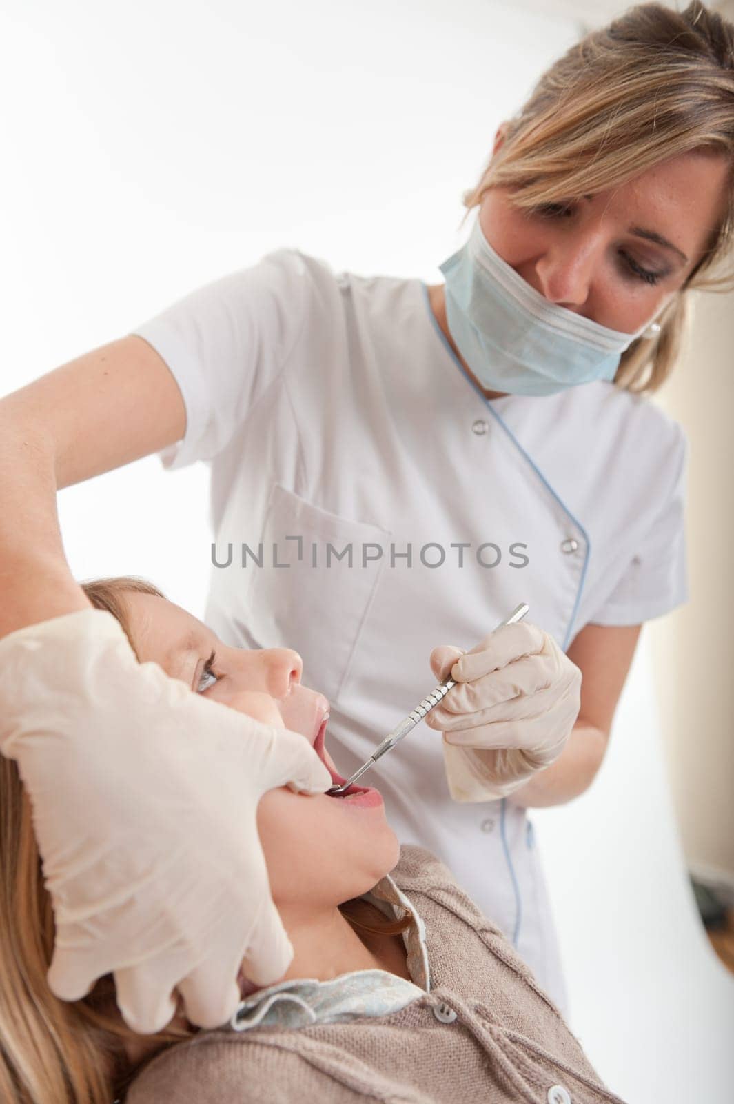 Dentist inspecting the teeth of a young girl