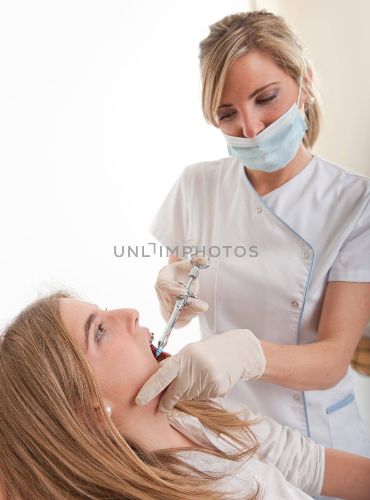 Female dentist injecting anesthetics to a young patient