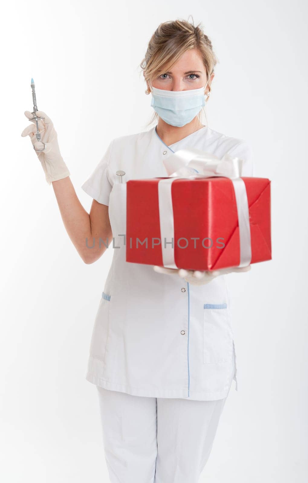 Attractive female dentist holding a syringe with one hand and a gift box with the other
