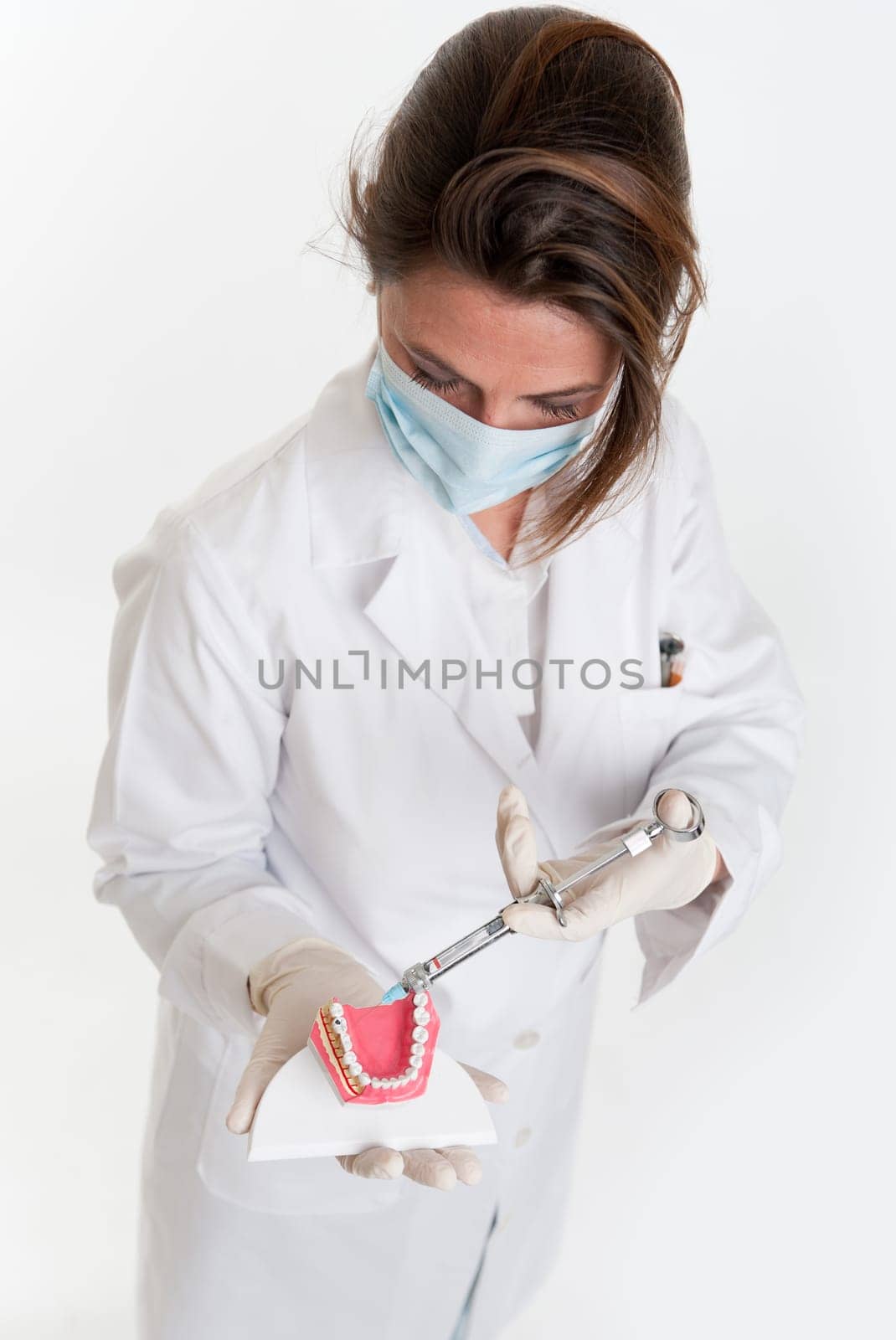 Female dentist holding a dentistry study model and a syringe