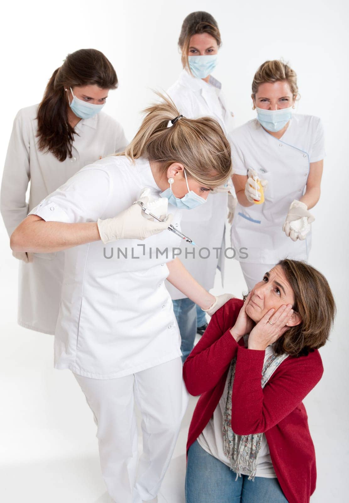 A woman on her knees surrounded by an aggressive group of female dentists