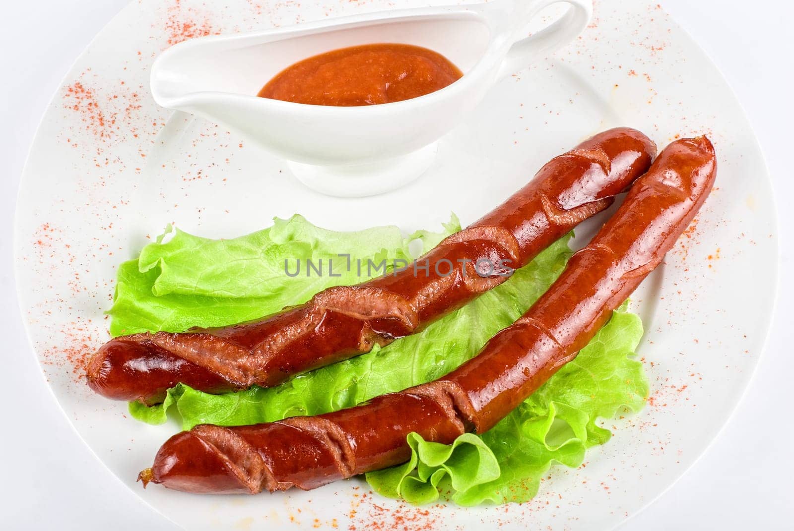 grilled sausage closeup with lettuce and sauce isolated on white