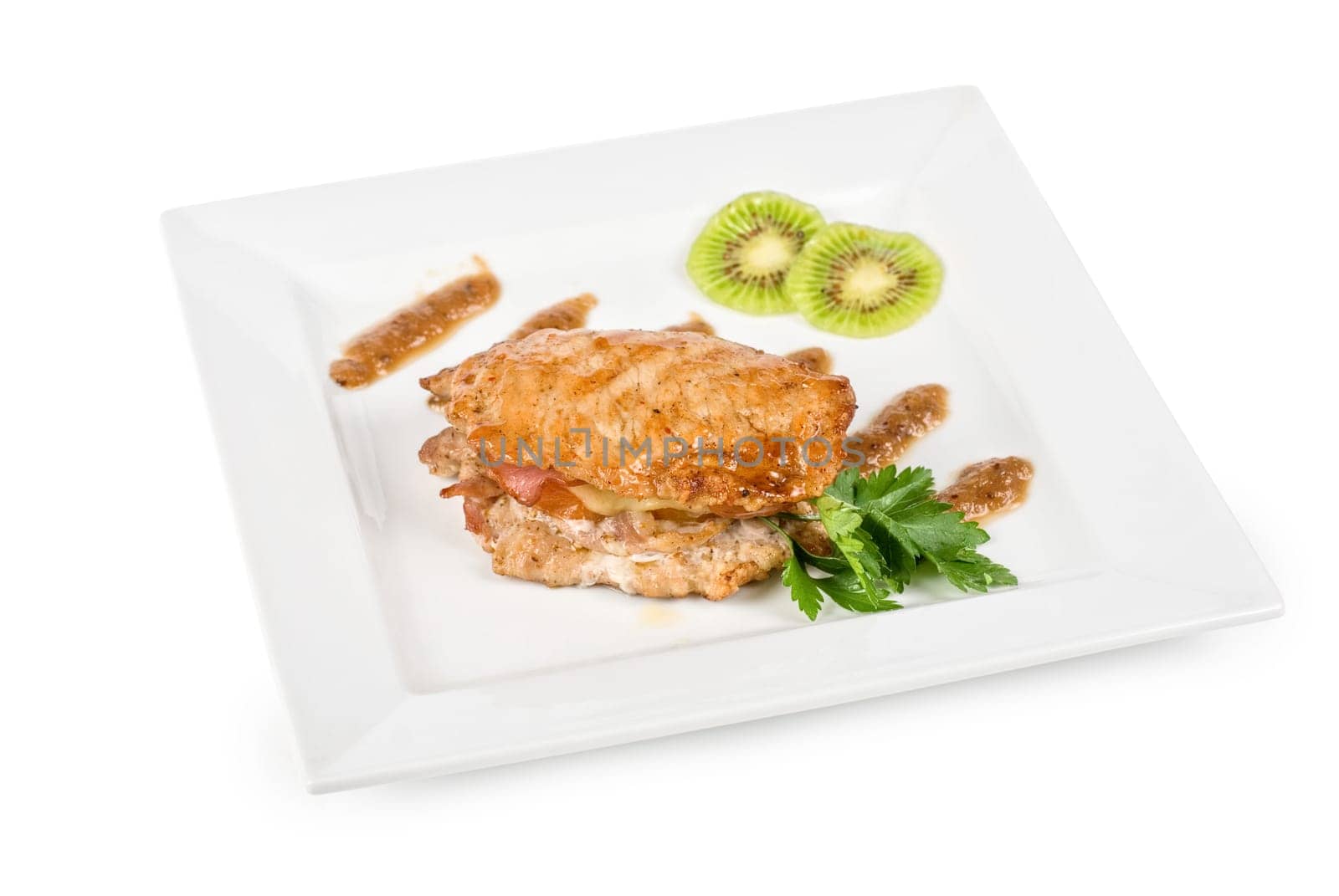 Cooked pork chop with kiwi and parsley on a white