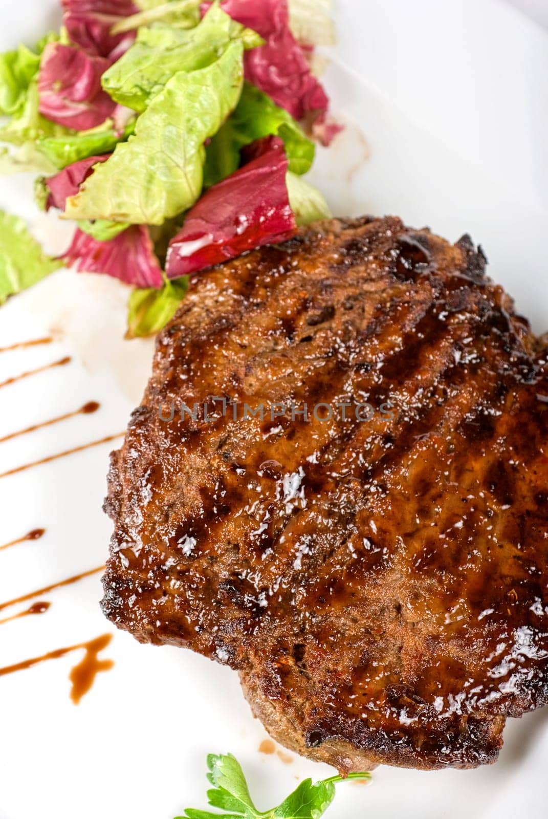 Beef steak on a white plate closeup with vegetables