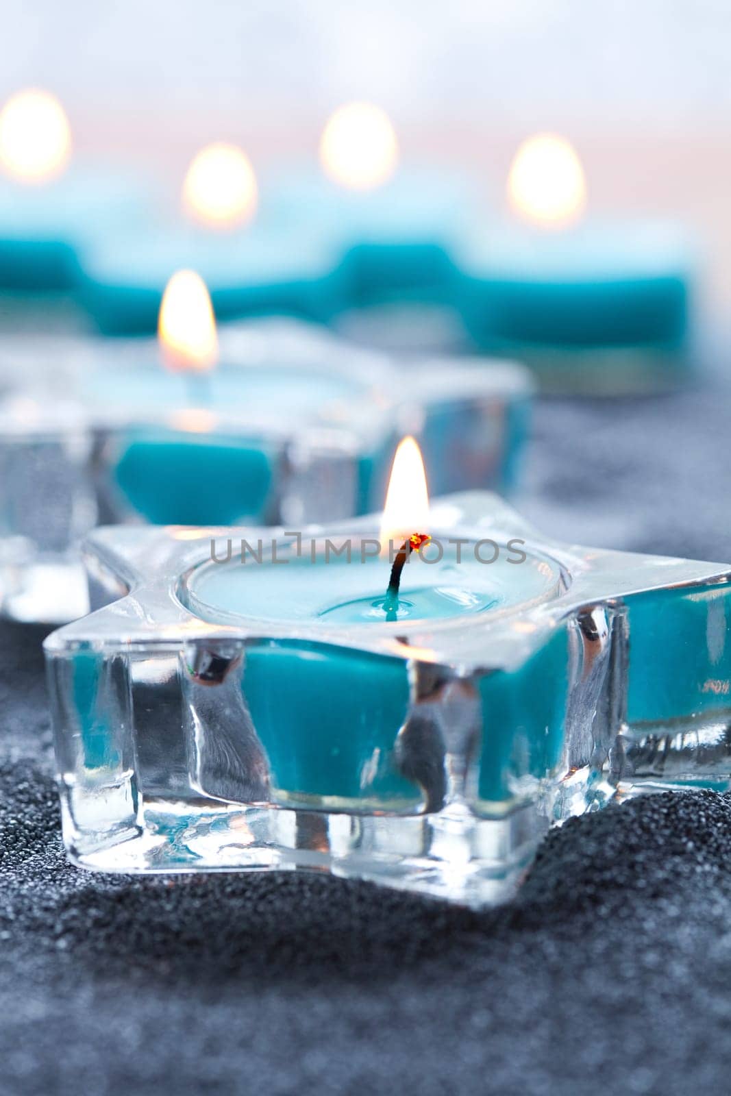 Close-up of blue candles in star shape holders on silver sand