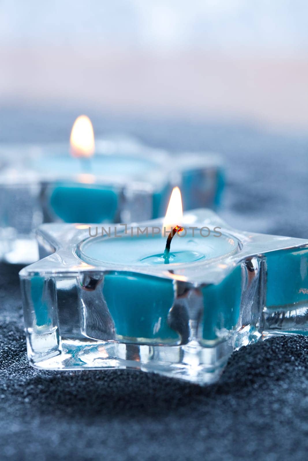 Close-up of blue candles in star shape holders on silver sand