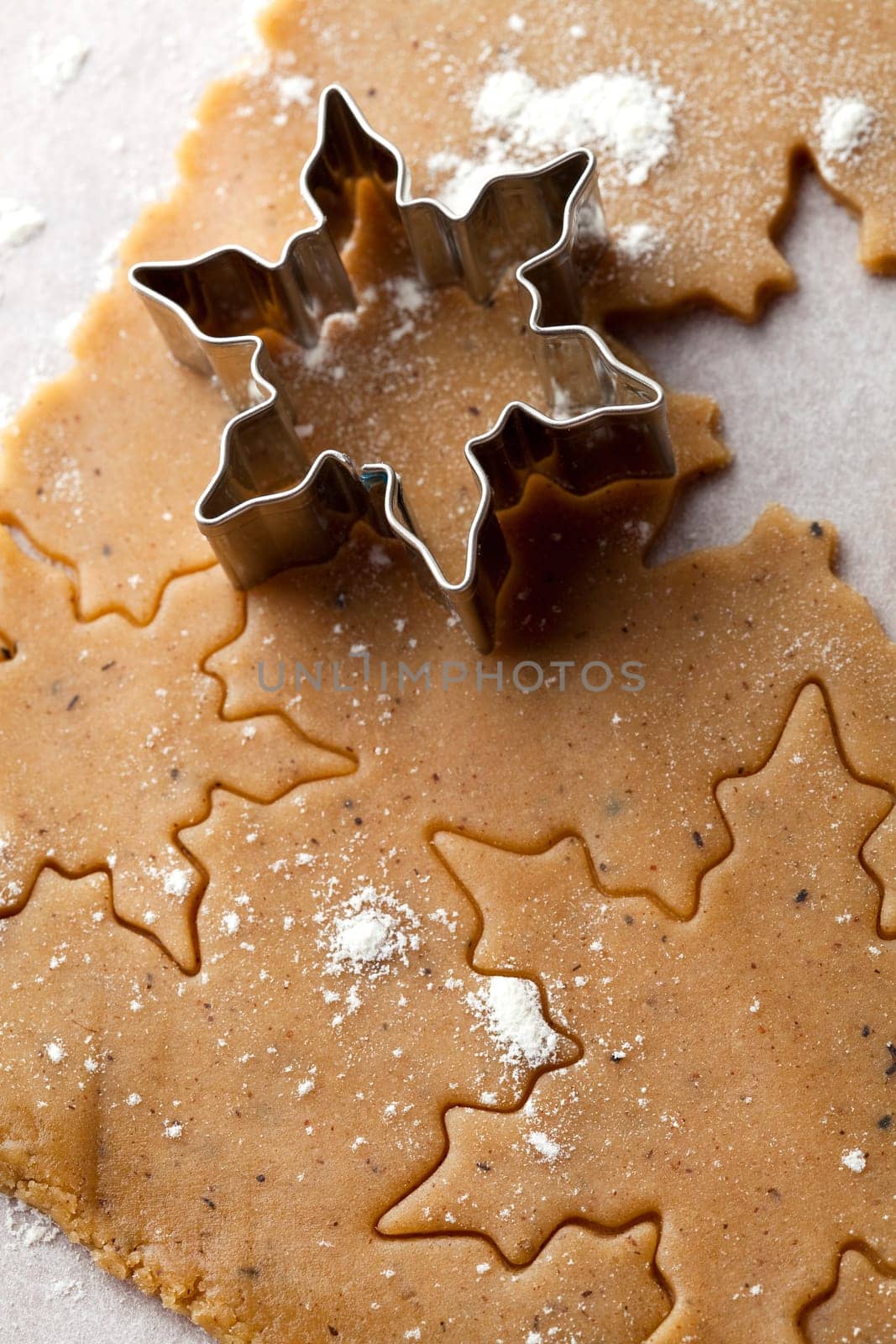 Making gingerbread cookies for Christmas. Gingerbread dough with star shapes and a cutter.