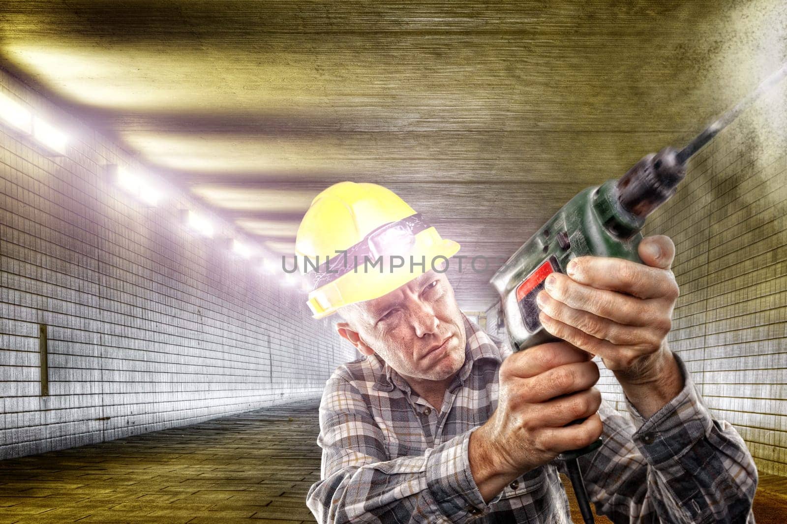 Craftsman with a drill works in a tunnel
