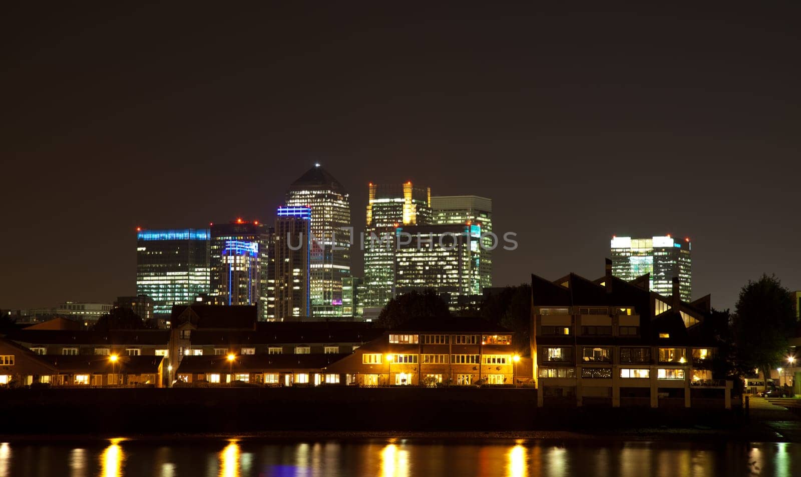 City skyscrapers behind residential houses at night