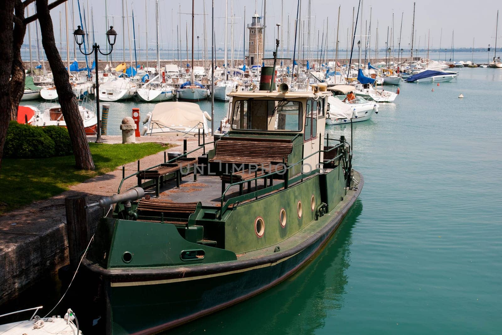 Small harbor with lighthouse and boats in Desenzano near lake Garda
