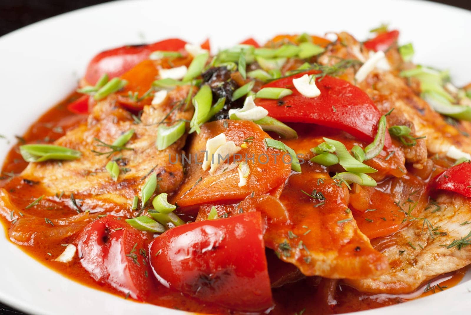 pork meat with tomato, pepper, prunes, garlic and green onion