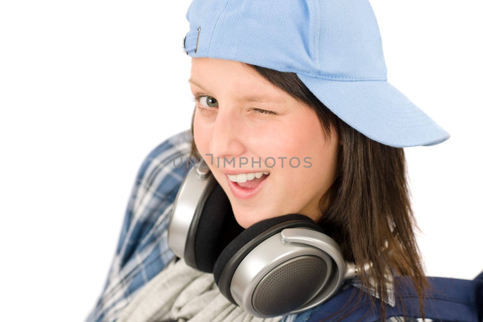 Smiling female teenager enjoy music with headphones and baseball cap