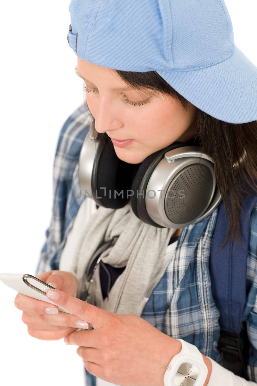 Smiling female teenager enjoy music with headphones dialing on phone