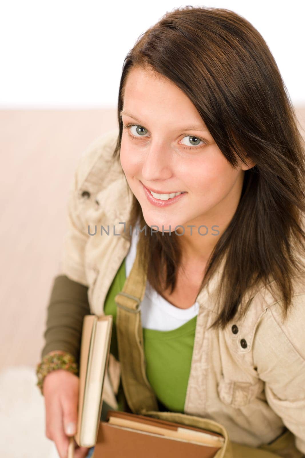 Student teenager girl holding books looking up to camera