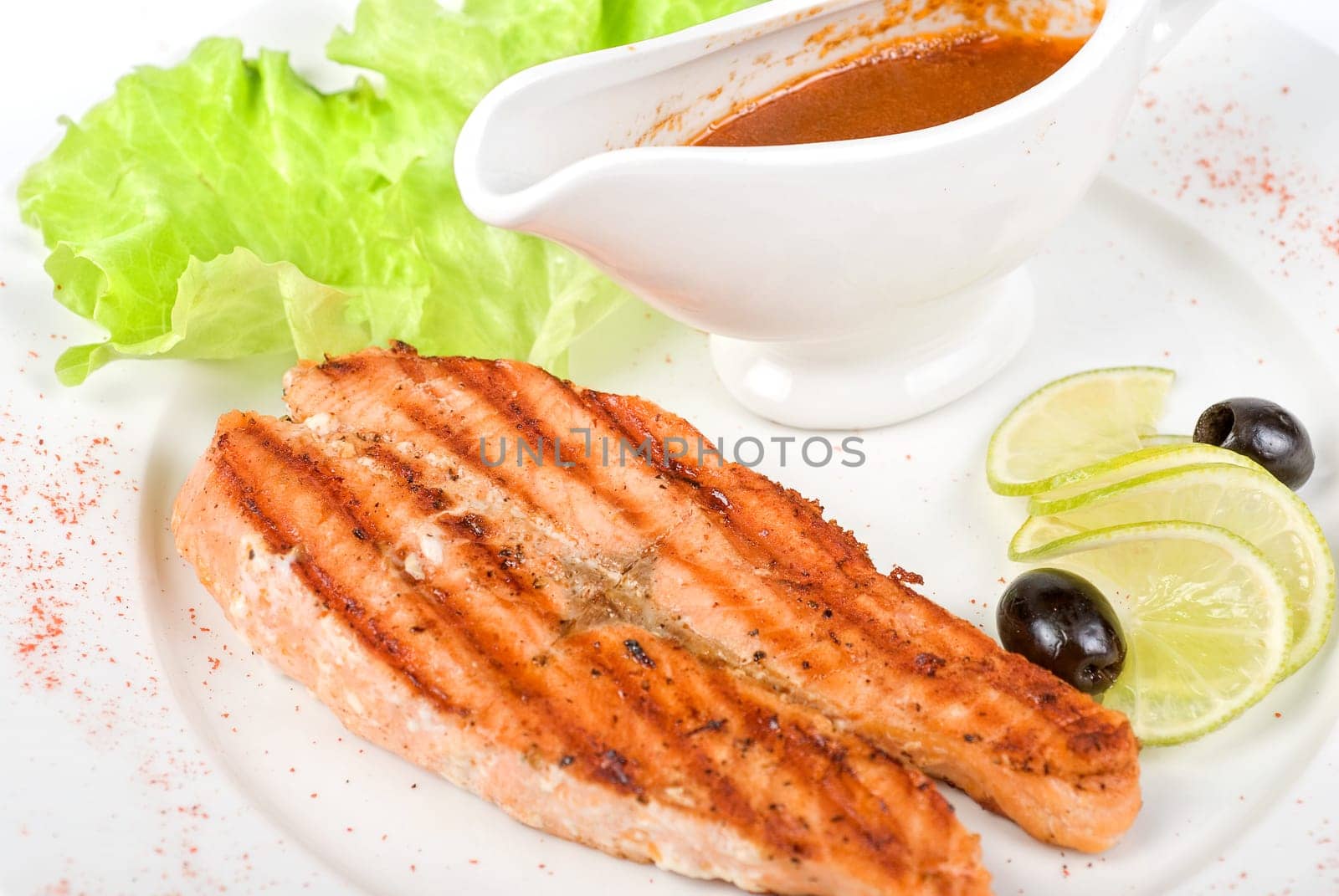 Grilled salmon steak with sauce,greens, lemon and olive