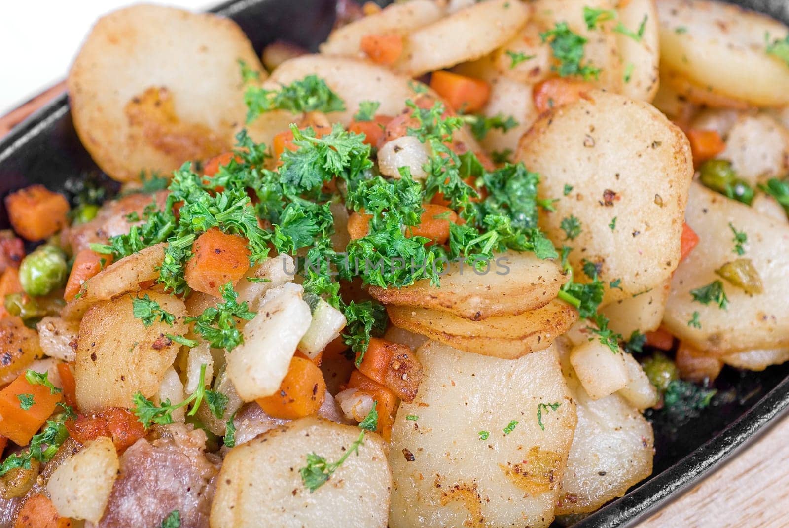 Fried potato with meat and vegetables on a white