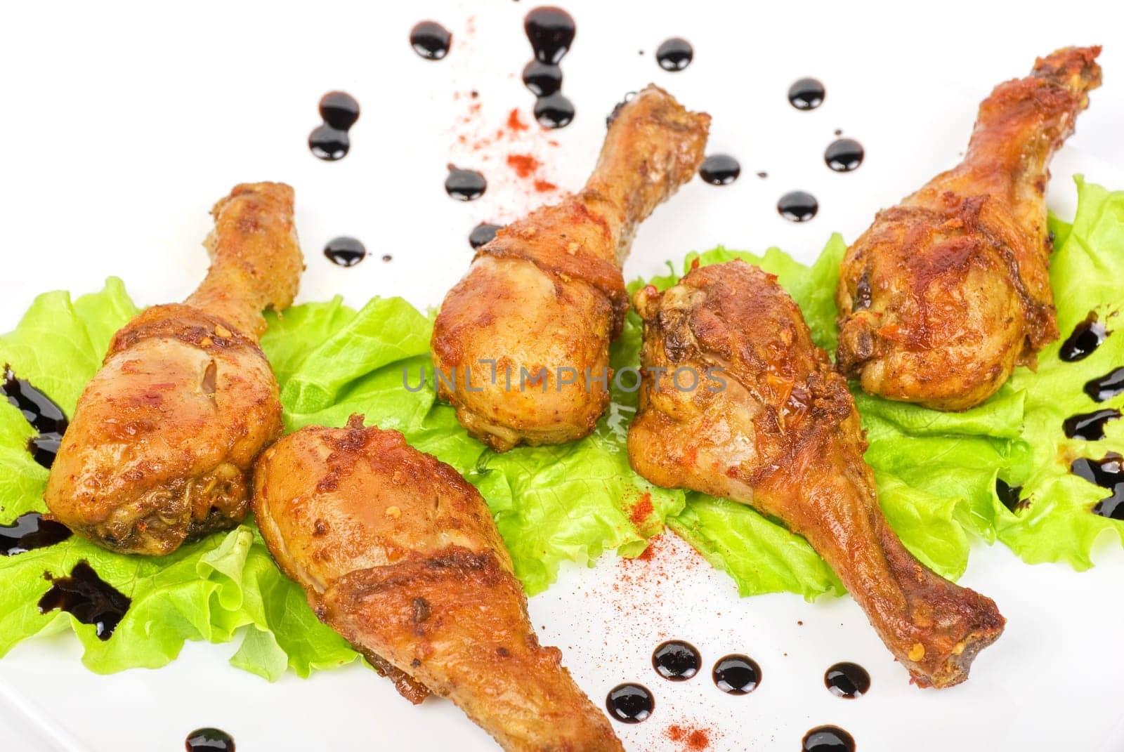 chicken drumstick closeup at white plate with lettuce