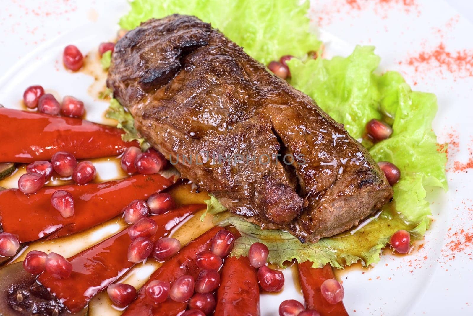 Roasted beef steak with pomegranate closeup at plate