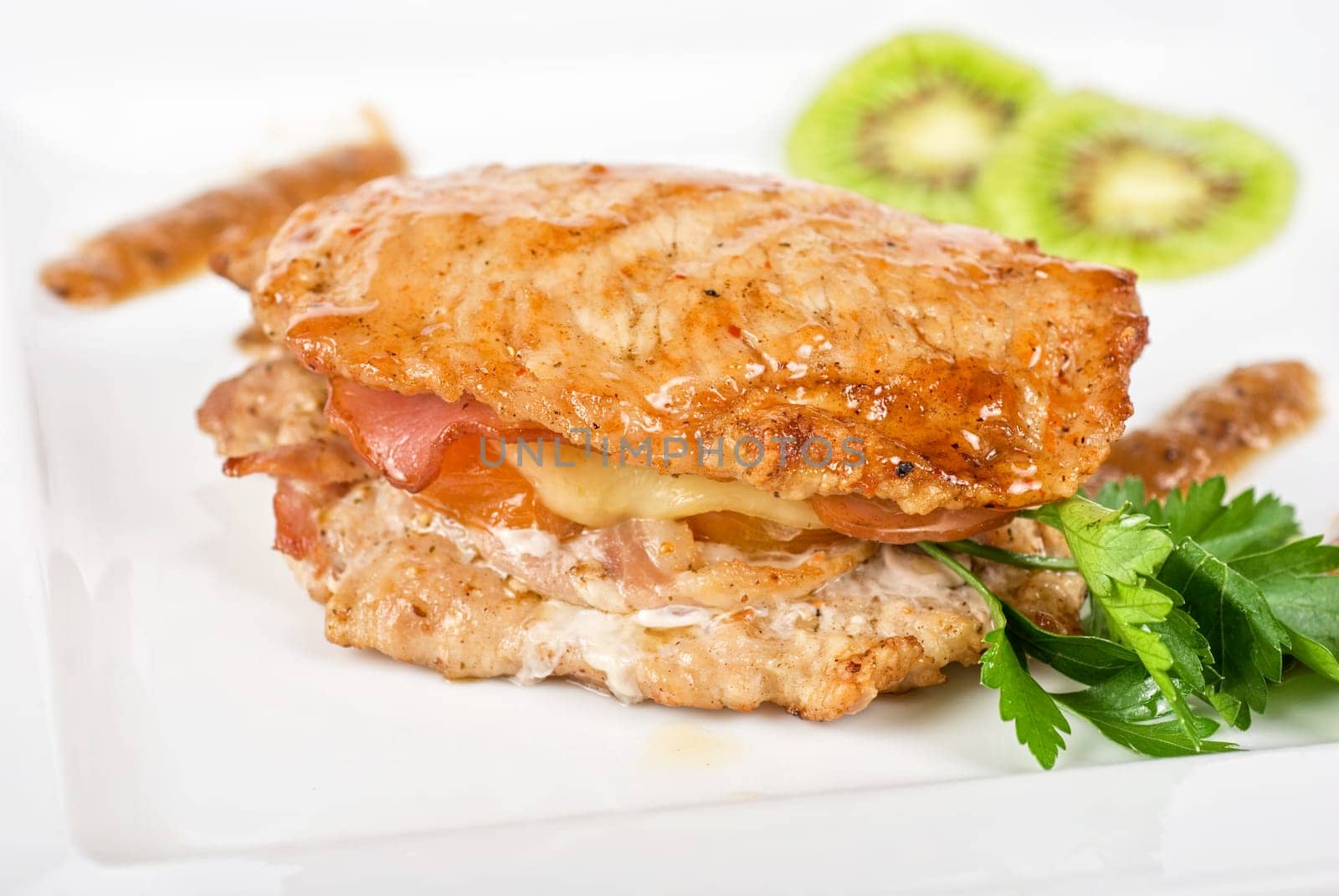 Cooked pork chop with kiwi and parsley on a white