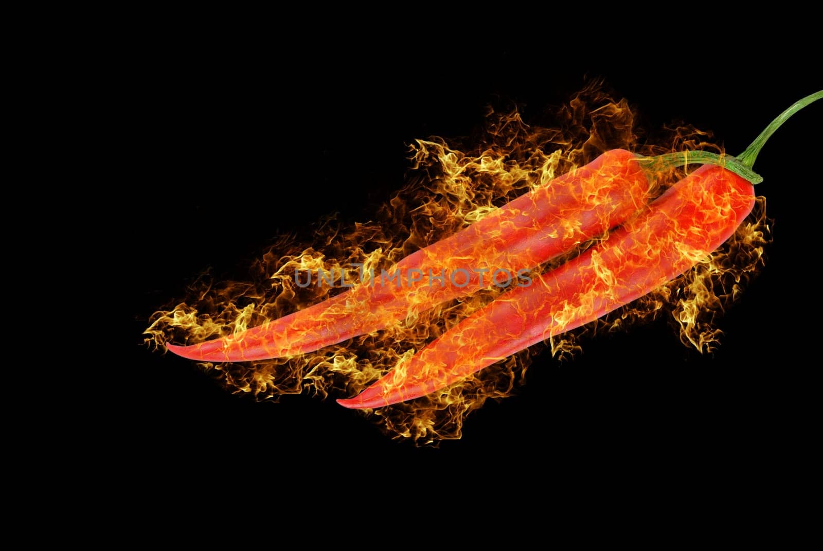 spicy red chilli peppers at fire on black background