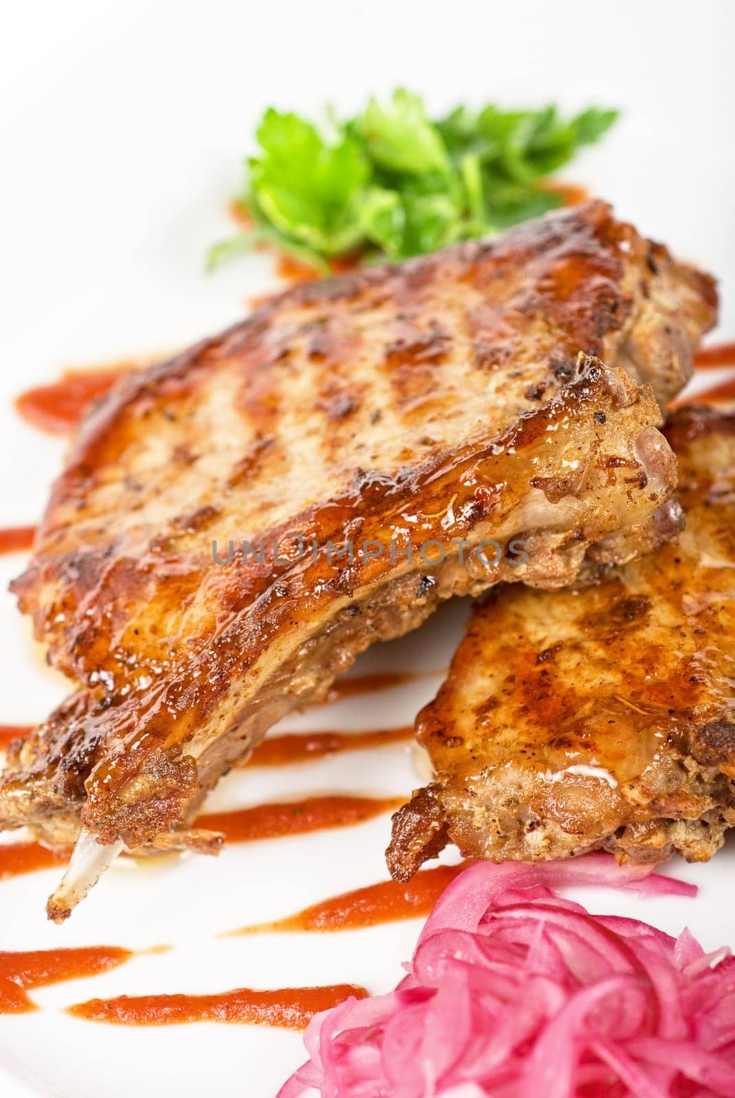 Cooked pork chop with kiwi and parsley on a white