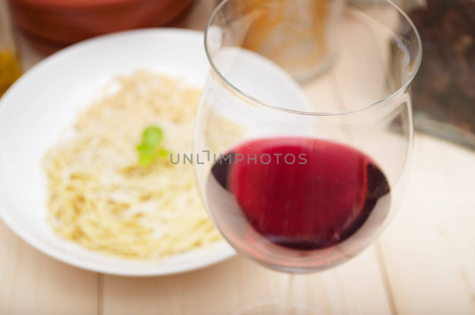 Italian Cuisine - Glass of Red Wine on Table in Front of Plate of Spaghetti - Shallow Depth of Field