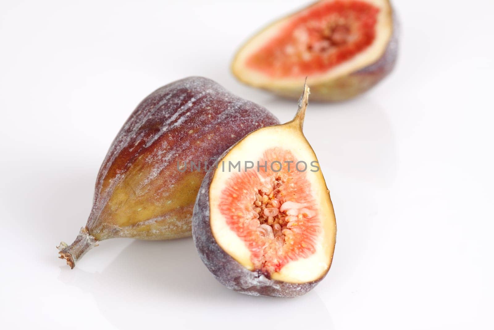 Whole and half figs on a white background
