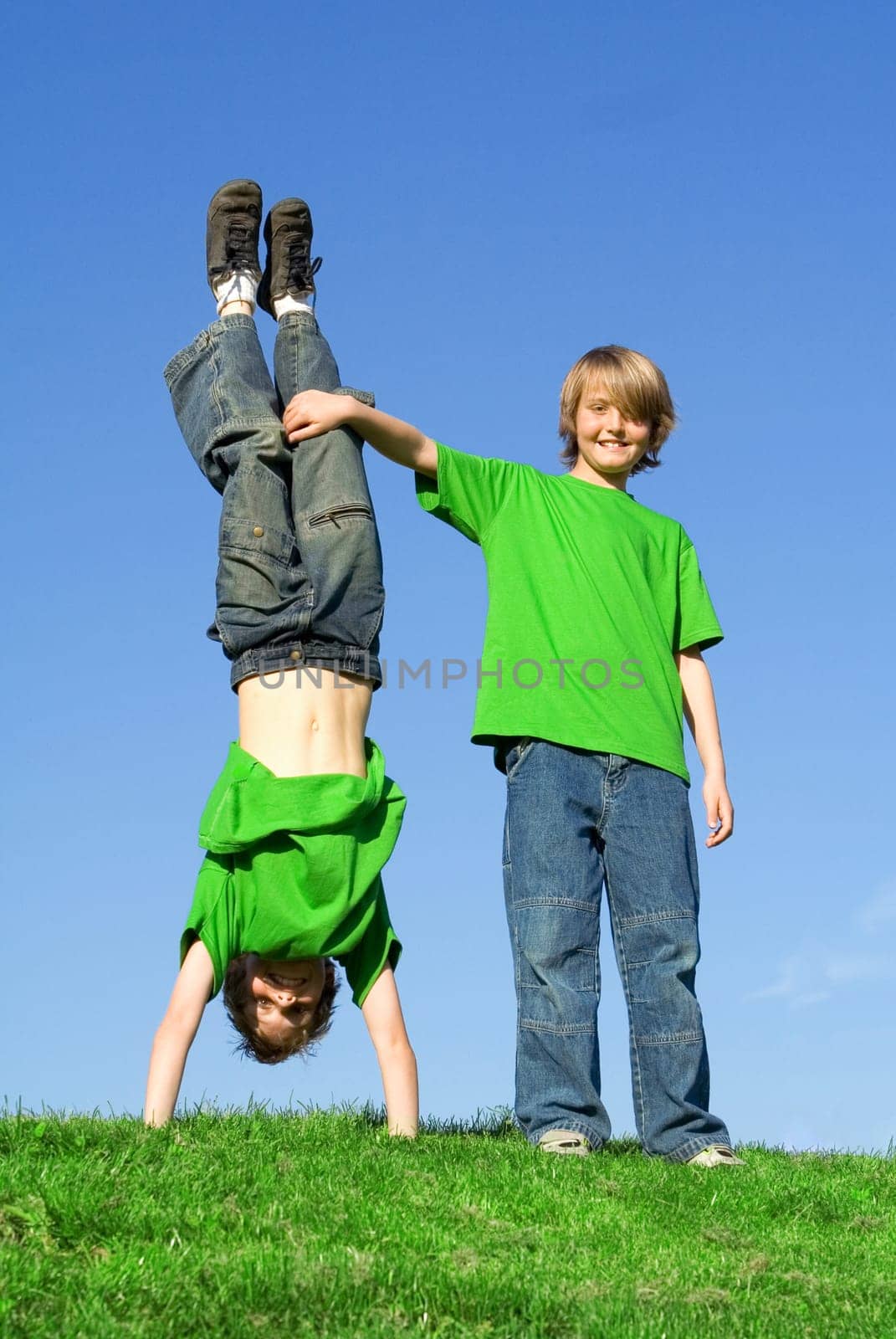 twins, twin brothers playing outside, in summer one upside, down.