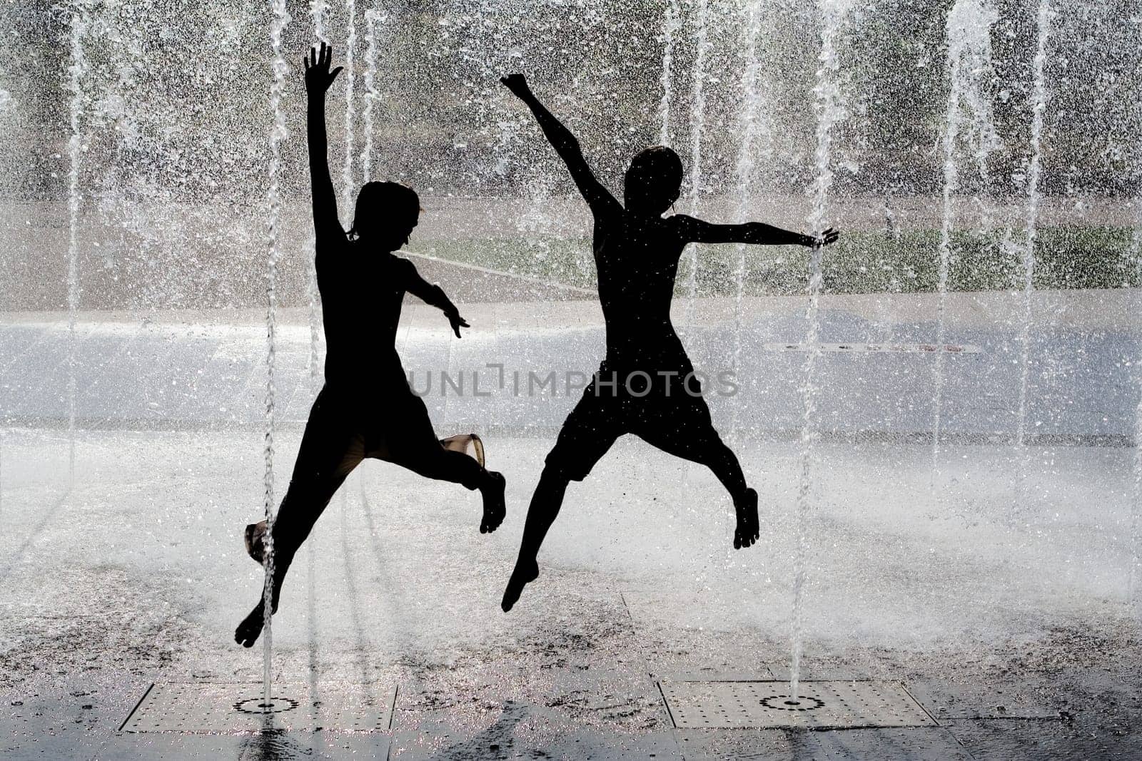 silhouette of kids jumping in cool fountain water