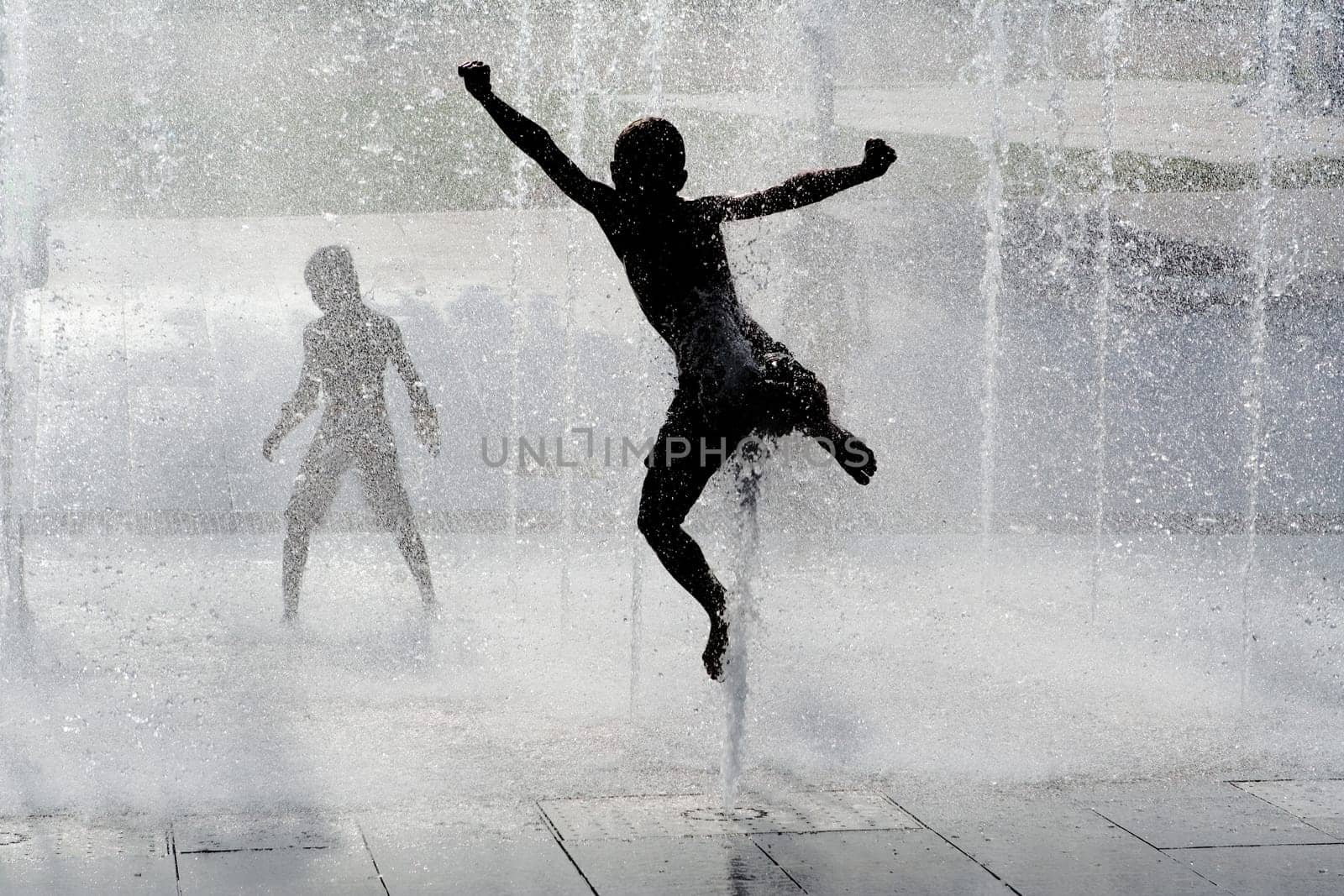 happy wet summer kids playing in water fountain