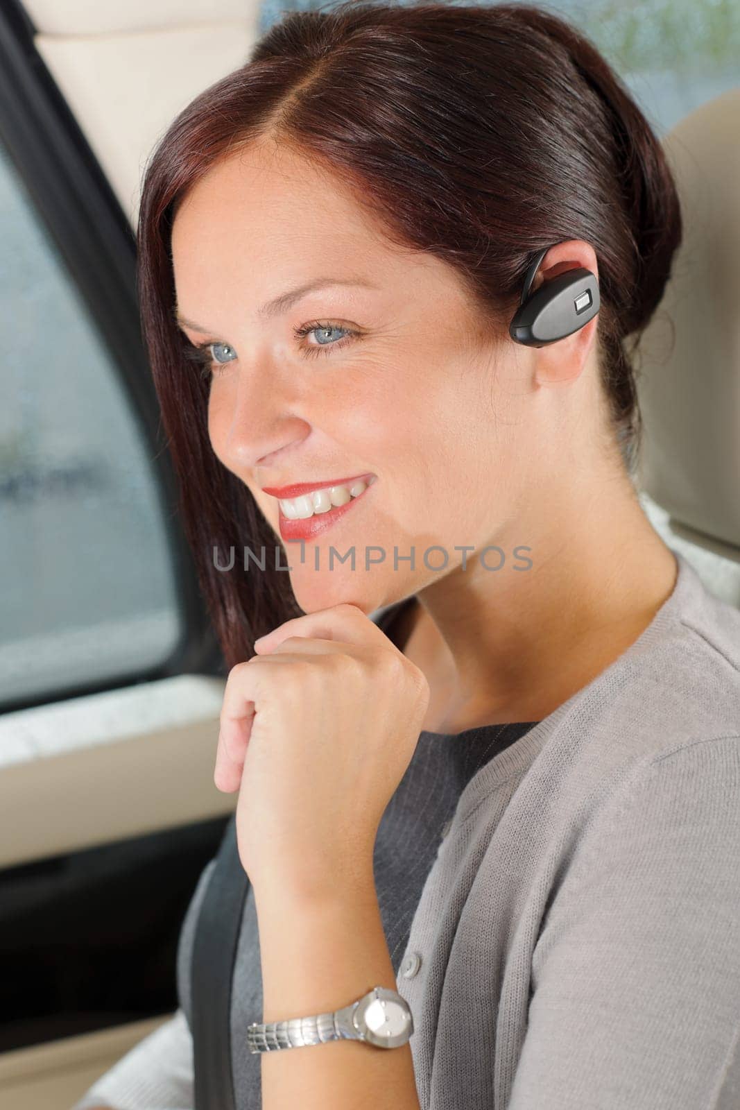 Attractive executive female manager sitting in car backseat calling hands-free