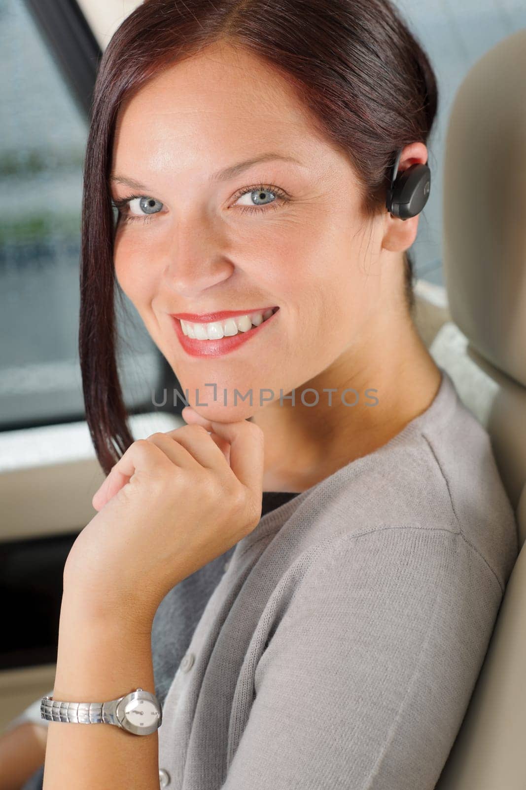 Attractive executive female manager sitting in car backseat calling hands-free