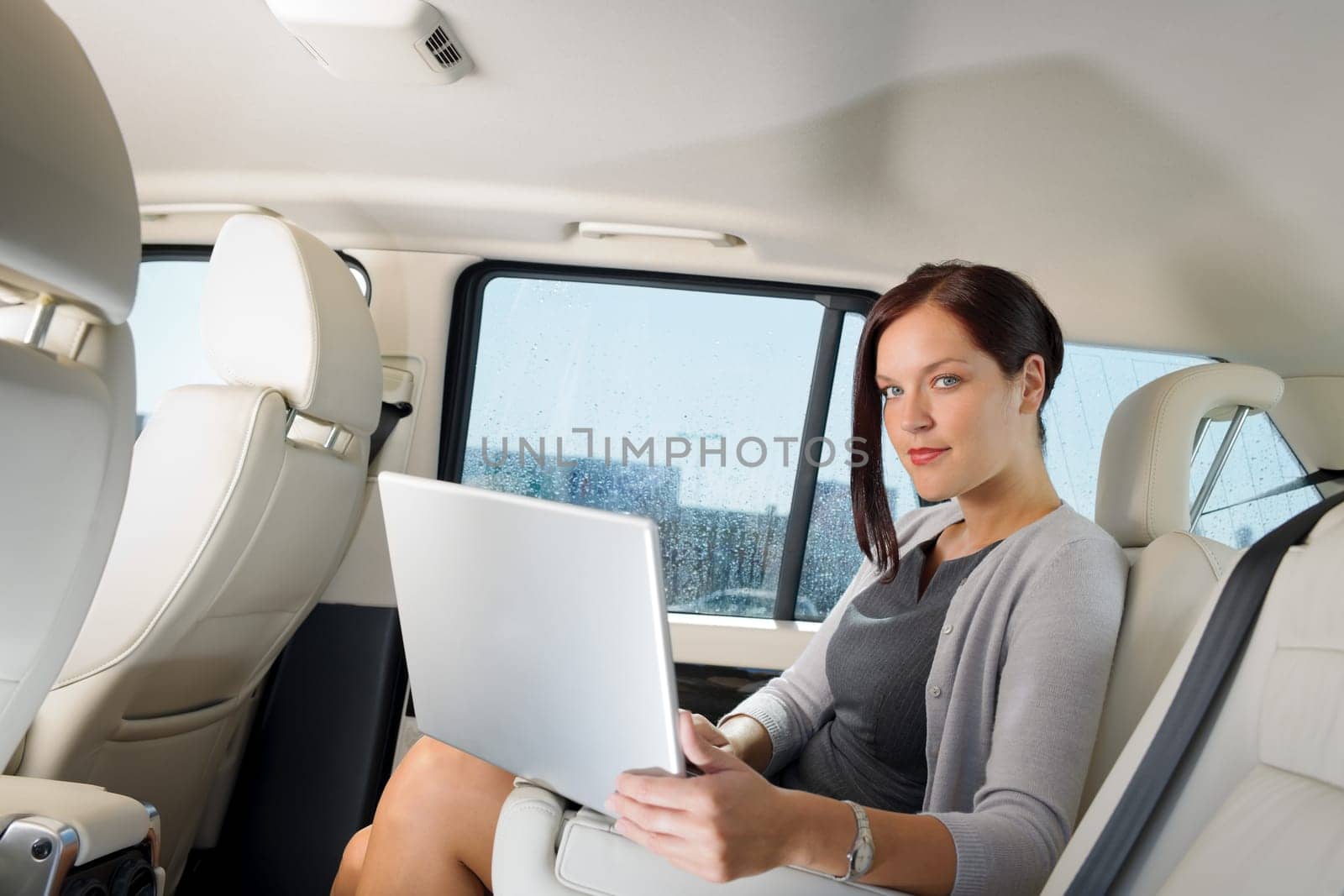 Executive woman manager working on laptop sitting car leather backseat