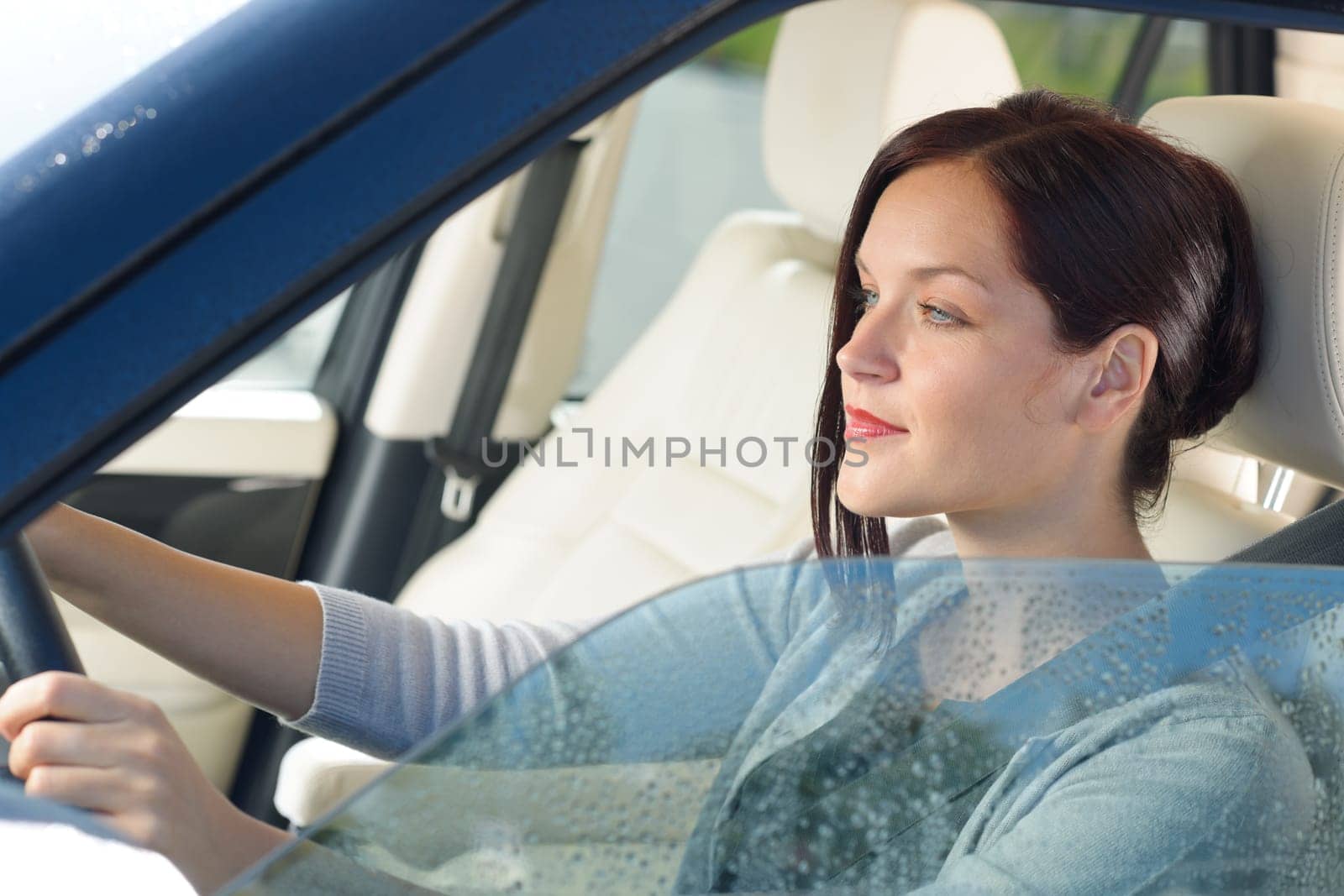 Attractive elegant businesswoman driving luxury new car concentrating