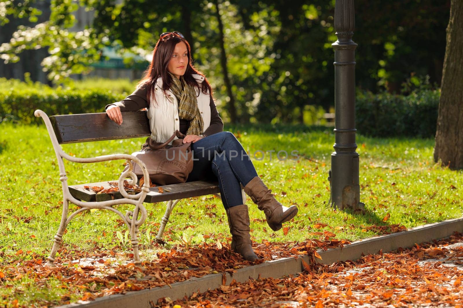 Autumn fashion outfit attractive woman sitting on park bench sunset