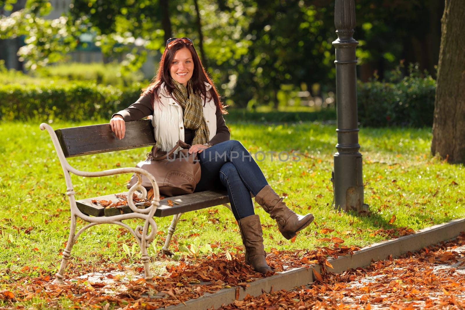 Autumn fashion outfit attractive woman sitting on park bench sunset