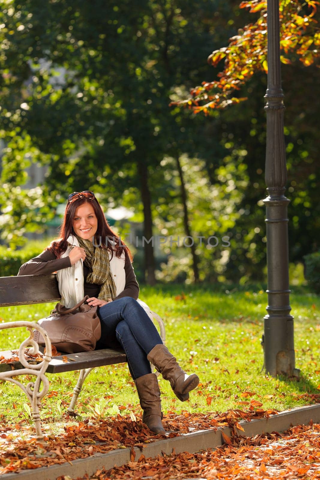 Autumn fashion outfit attractive woman sitting on park bench sunset