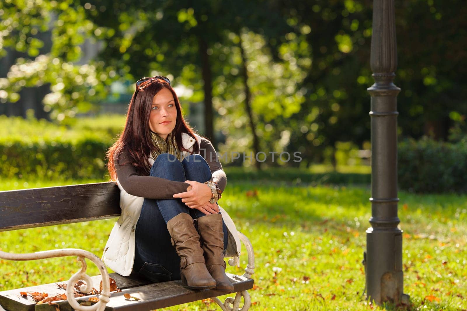Autumn fashion outfit attractive woman sitting on park bench sunset