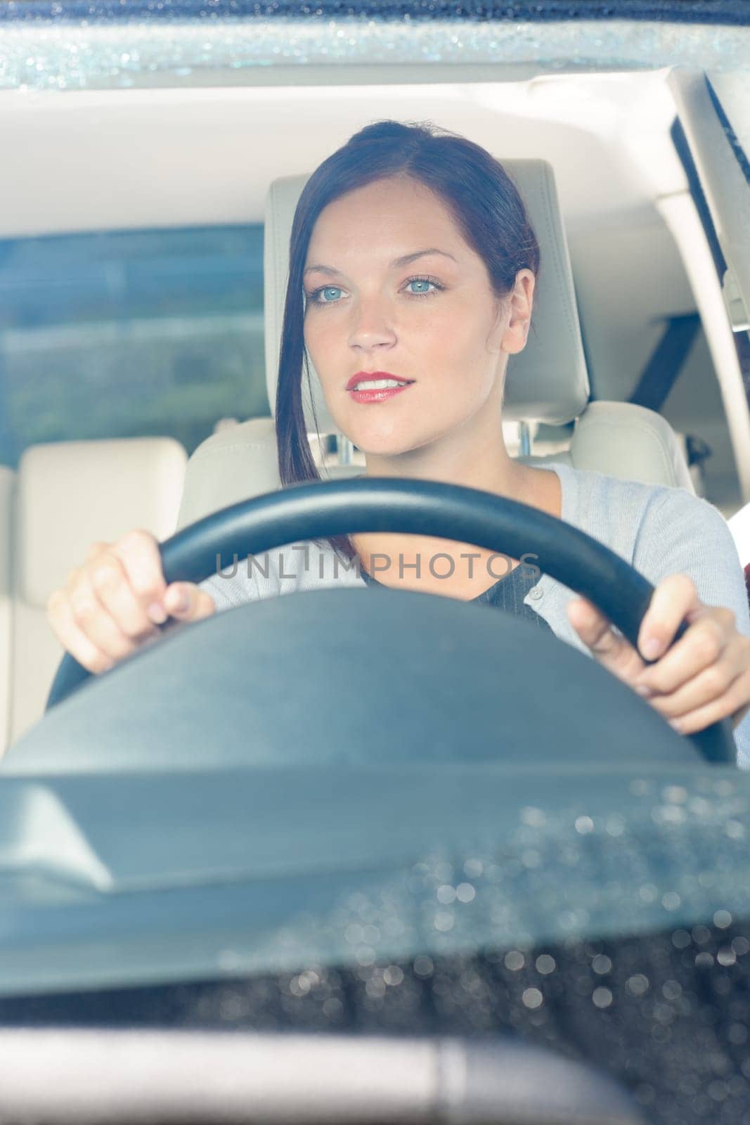 Attractive elegant businesswoman driving luxury new car smiling behind window