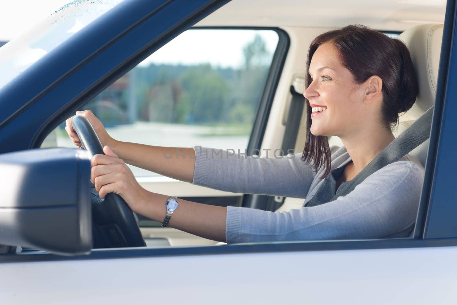 Attractive elegant businesswoman driving luxury new car concentrating