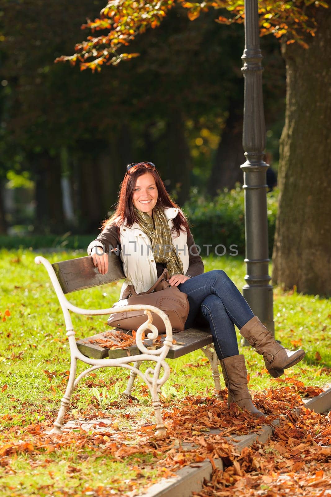 Autumn fashion outfit attractive woman sitting on park bench sunset