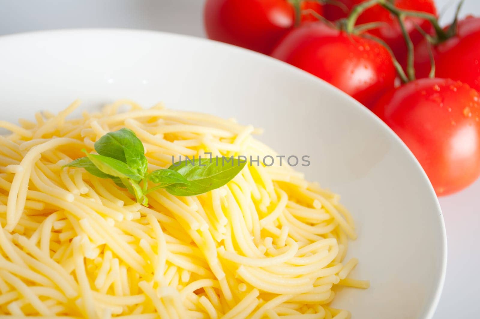Spaghetti With Basil on White Plate and Fresh Tomatoes