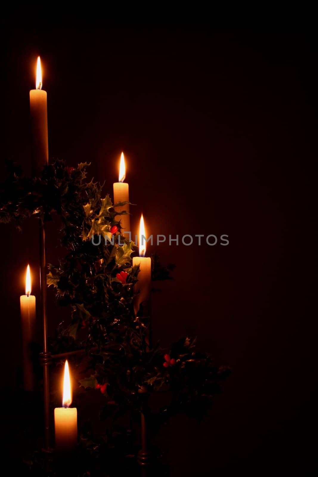 lit christmas holiday candles with holly