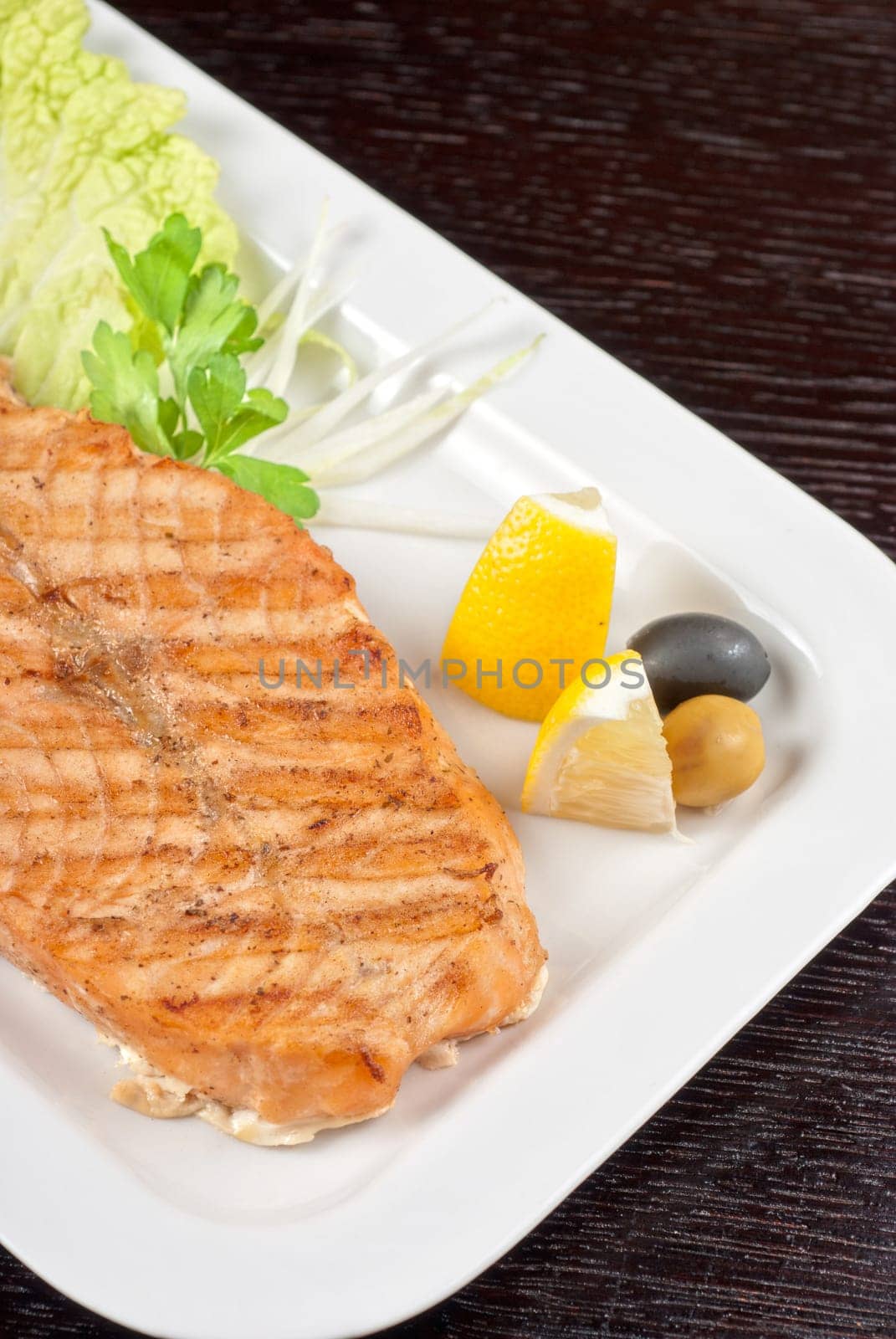 Grilled salmon steak with greens,onion, lemon, lime and olive
