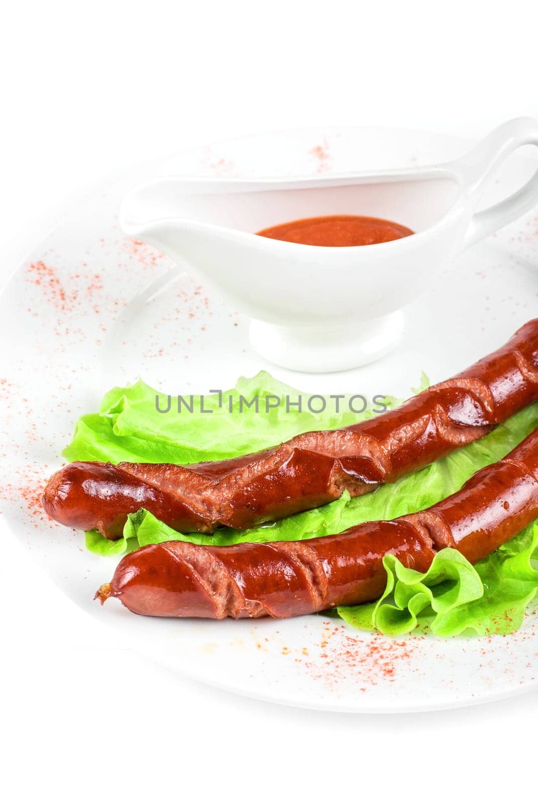 grilled sausage closeup with lettuce and sauce isolated on white